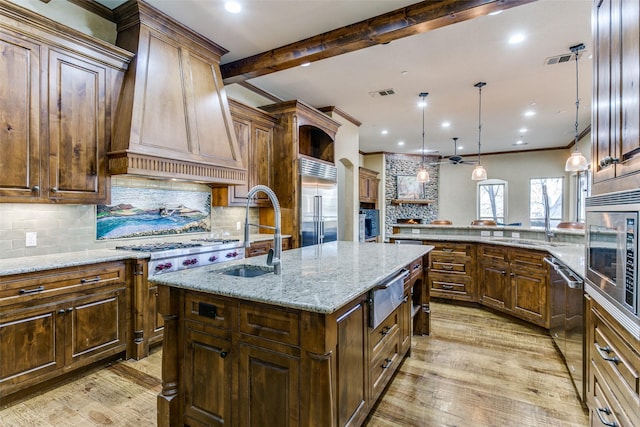 kitchen featuring a warming drawer, custom range hood, visible vents, a sink, and built in appliances