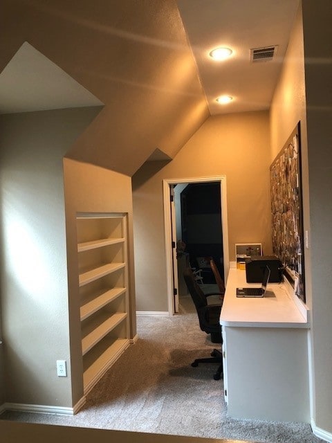 unfurnished office featuring vaulted ceiling, carpet, visible vents, and baseboards