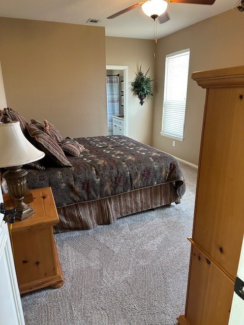 carpeted bedroom with a ceiling fan, visible vents, and baseboards