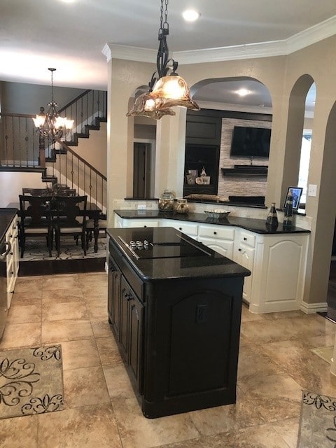 kitchen with an inviting chandelier, dark countertops, black electric cooktop, and arched walkways