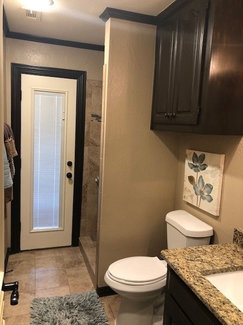 bathroom featuring visible vents, toilet, a tile shower, vanity, and tile patterned flooring