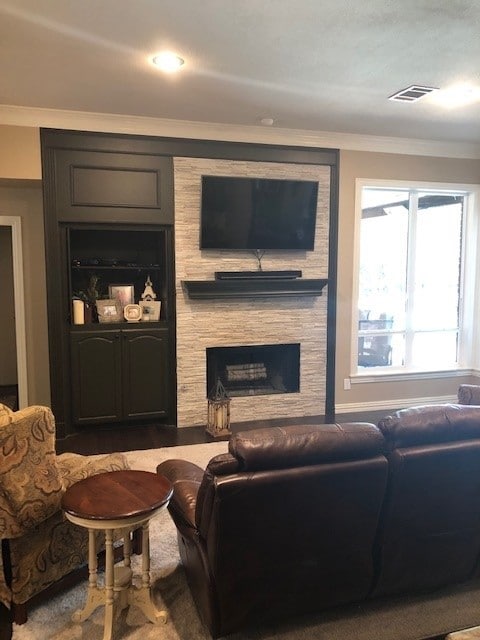 living room featuring crown molding, visible vents, and a fireplace