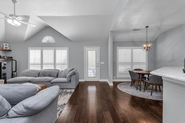 living area with visible vents, vaulted ceiling, dark wood finished floors, and ceiling fan with notable chandelier