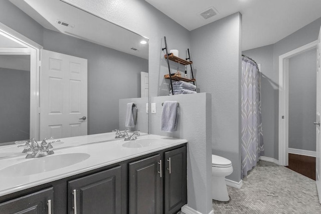 bathroom featuring toilet, a sink, and visible vents