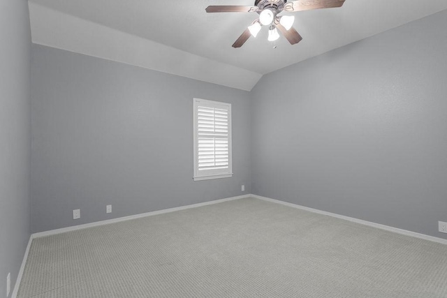 spare room featuring a ceiling fan, carpet, vaulted ceiling, and baseboards