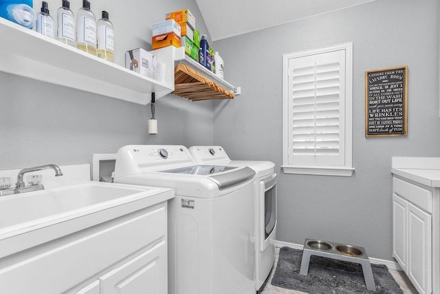 laundry area featuring separate washer and dryer, a sink, cabinet space, and baseboards