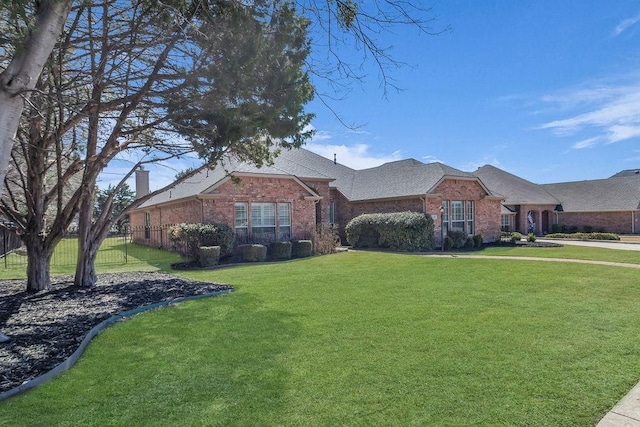 ranch-style house featuring a front yard, brick siding, fence, and roof with shingles