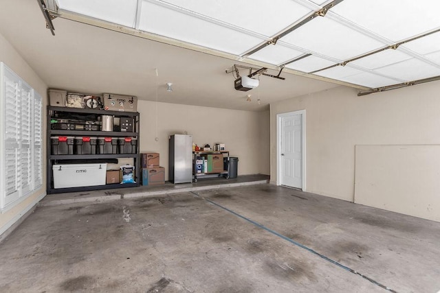 garage featuring freestanding refrigerator and a garage door opener