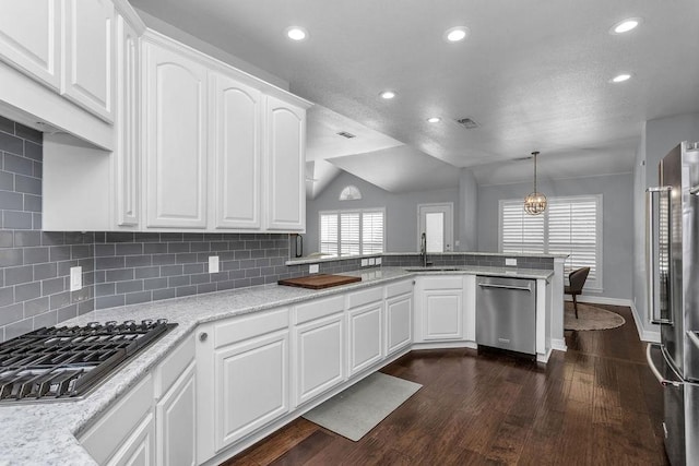 kitchen with decorative backsplash, appliances with stainless steel finishes, dark wood-type flooring, a peninsula, and a sink