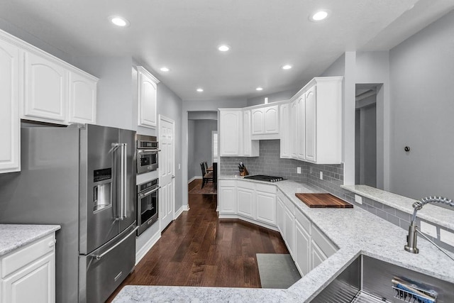 kitchen featuring tasteful backsplash, dark wood finished floors, high end fridge, a sink, and recessed lighting