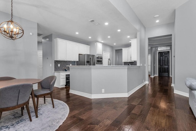 kitchen featuring dark wood-type flooring, visible vents, white cabinets, appliances with stainless steel finishes, and tasteful backsplash