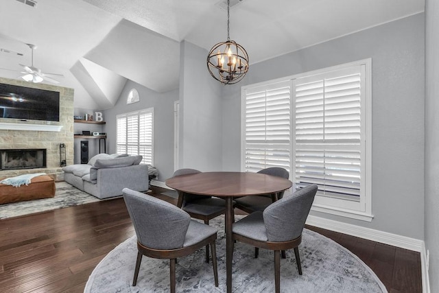 dining room featuring dark wood finished floors, a fireplace, lofted ceiling, and baseboards