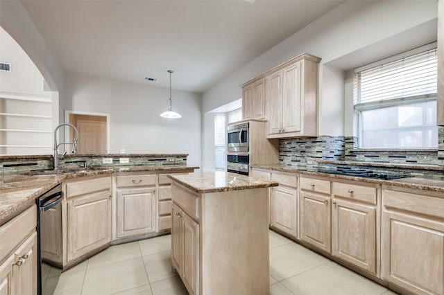 kitchen featuring appliances with stainless steel finishes, light stone counters, a sink, and light brown cabinetry