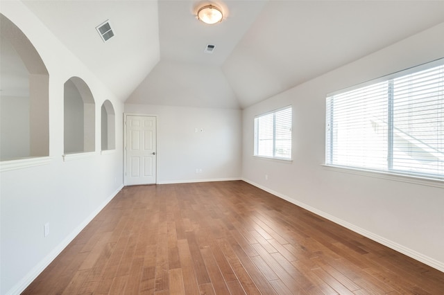 spare room featuring lofted ceiling, wood finished floors, visible vents, and baseboards