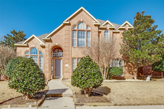 traditional home featuring brick siding and roof with shingles