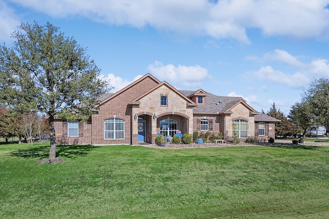 french provincial home with stone siding, brick siding, and a front lawn