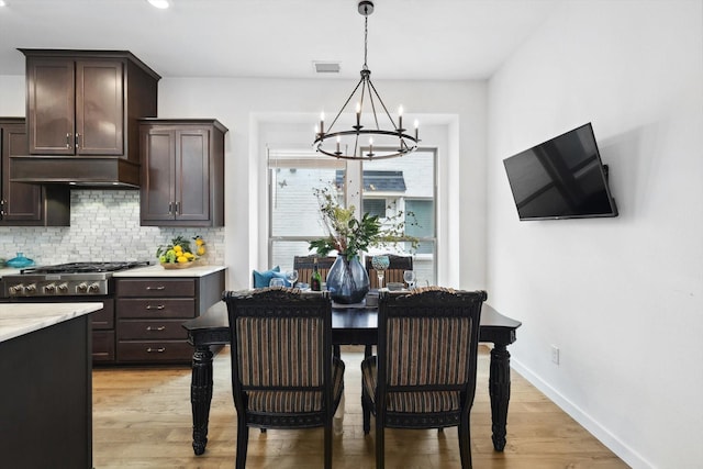 dining area featuring a chandelier, visible vents, light wood-style flooring, and baseboards