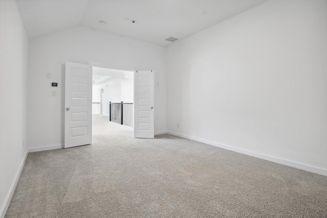 carpeted empty room with vaulted ceiling and baseboards