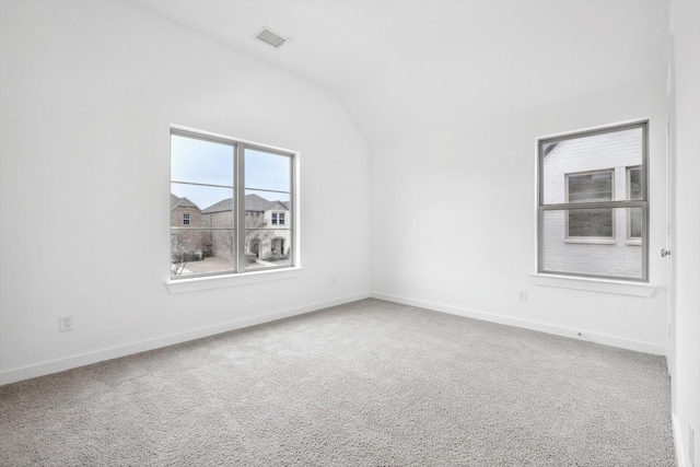 empty room featuring vaulted ceiling, carpet, visible vents, and baseboards