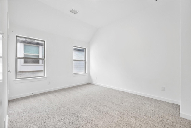 carpeted spare room featuring vaulted ceiling, visible vents, and baseboards