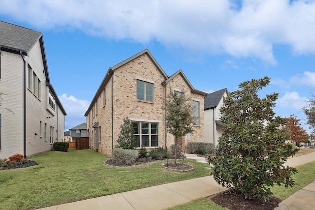 view of front of house featuring fence, a front lawn, and brick siding