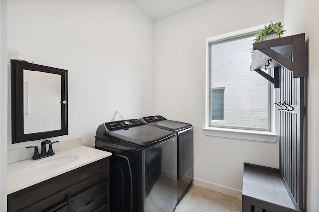 clothes washing area featuring light tile patterned floors, washing machine and dryer, baseboards, and a sink