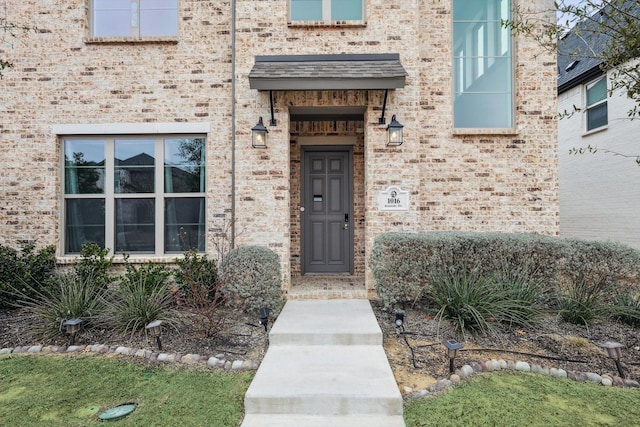 view of exterior entry featuring brick siding