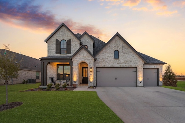 french provincial home featuring concrete driveway, a lawn, central air condition unit, a porch, and brick siding