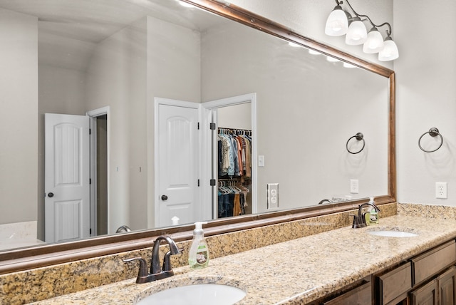 bathroom with double vanity, a spacious closet, and a sink