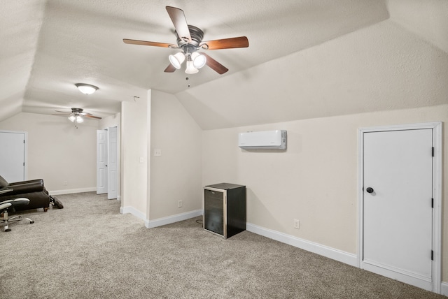 additional living space with baseboards, light colored carpet, lofted ceiling, a wall mounted air conditioner, and a textured ceiling