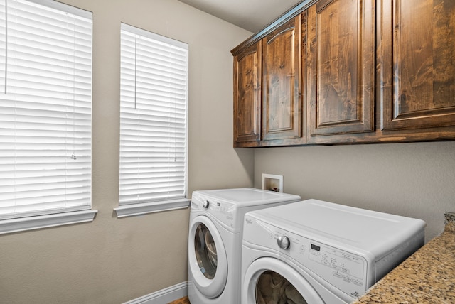 laundry area featuring separate washer and dryer, cabinet space, and baseboards