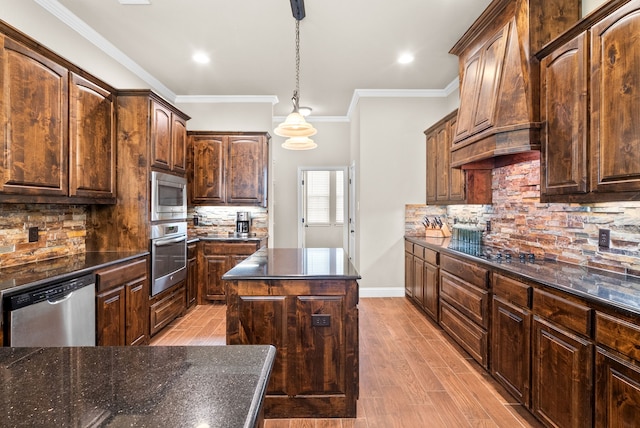 kitchen featuring a kitchen island, appliances with stainless steel finishes, decorative backsplash, light wood finished floors, and crown molding