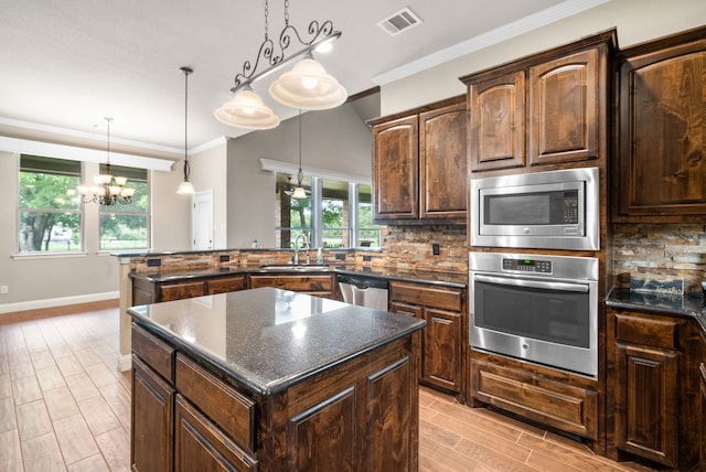 kitchen featuring visible vents, backsplash, appliances with stainless steel finishes, a sink, and a kitchen island