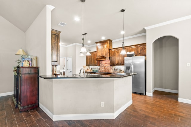 kitchen featuring arched walkways, visible vents, dark countertops, and stainless steel fridge with ice dispenser