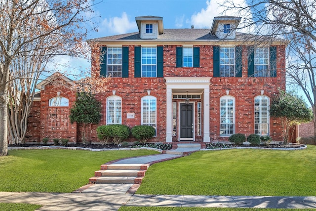 colonial-style house featuring a front lawn and brick siding