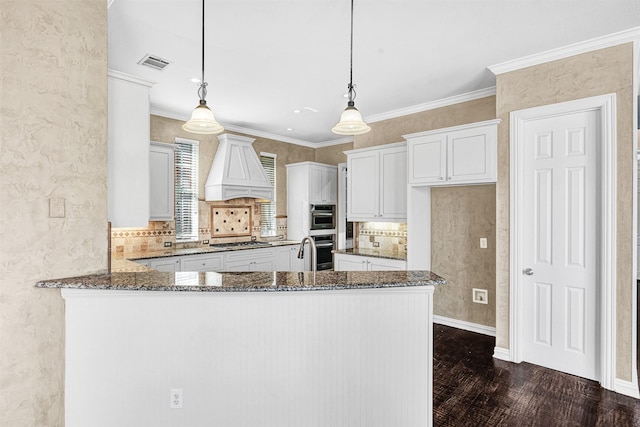 kitchen featuring visible vents, dark stone countertops, custom exhaust hood, and gas stovetop