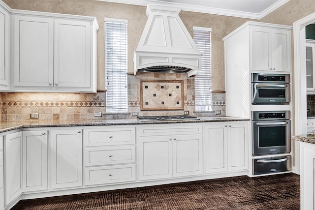 kitchen featuring crown molding, a warming drawer, custom range hood, appliances with stainless steel finishes, and light stone countertops