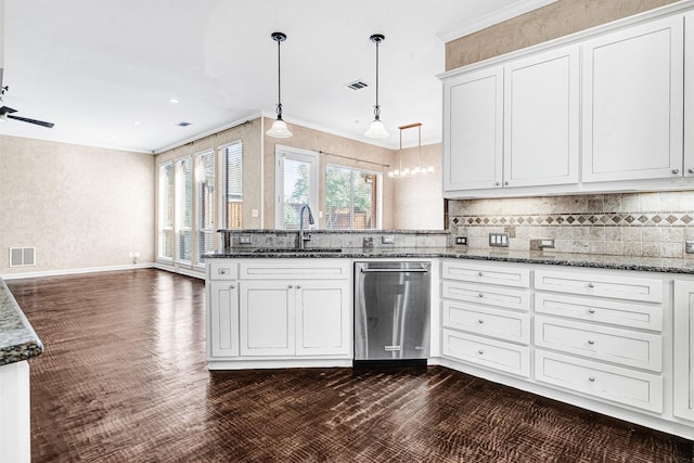 kitchen with dark wood-style floors, tasteful backsplash, ornamental molding, a sink, and a peninsula