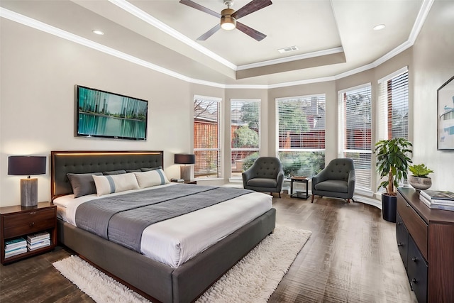 bedroom with a tray ceiling, crown molding, visible vents, and wood finished floors