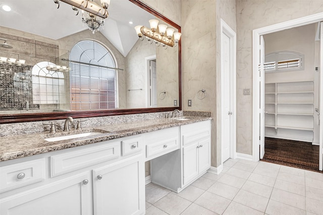 bathroom featuring lofted ceiling, double vanity, a sink, and tile patterned floors