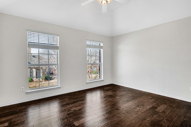 spare room with vaulted ceiling, dark wood-style flooring, a ceiling fan, and baseboards