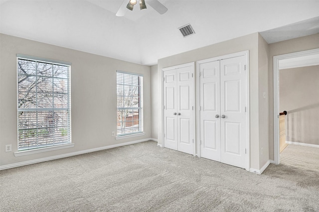 unfurnished bedroom featuring multiple closets, visible vents, carpet flooring, and multiple windows