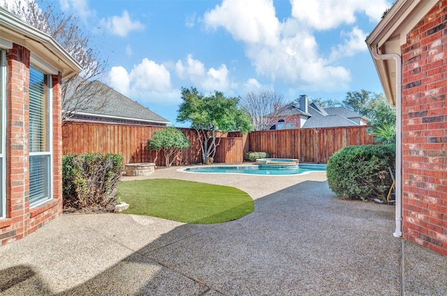 view of yard with a patio area, a fenced backyard, and a pool with connected hot tub