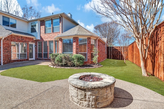 back of property with a fire pit, a patio area, brick siding, and a fenced backyard