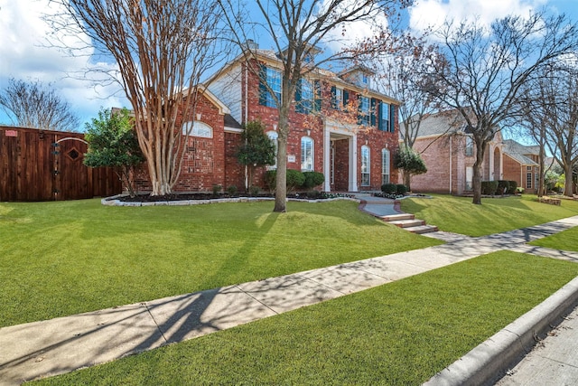 view of front of property featuring brick siding, a front lawn, and fence