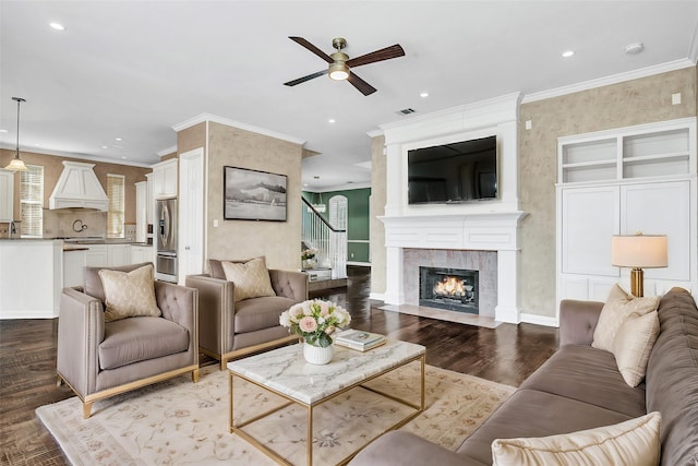 living room with stairway, ornamental molding, a large fireplace, wood finished floors, and baseboards