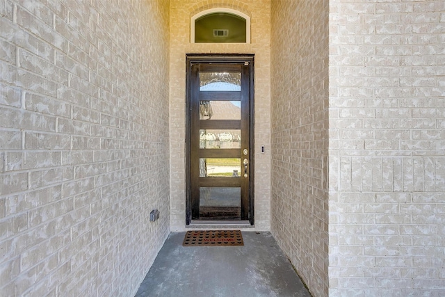 view of exterior entry featuring visible vents and brick siding