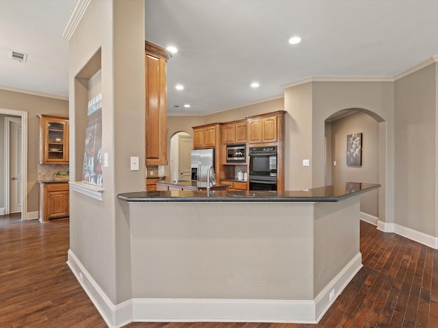 kitchen featuring arched walkways, stainless steel appliances, dark wood-type flooring, and visible vents