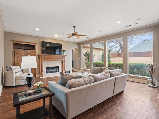 living area with dark wood-style floors, visible vents, and ornamental molding