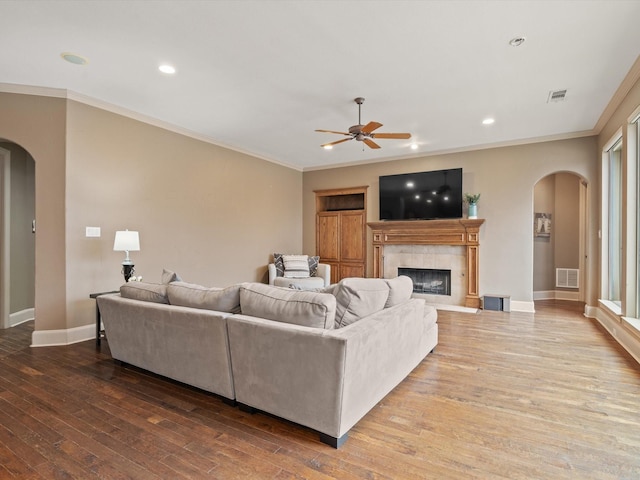 living area featuring arched walkways, wood finished floors, visible vents, and crown molding